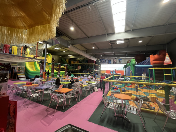 Vue d'ensemble de l'aire de jeux : gonflables, labyrinthe et tables pour les parents